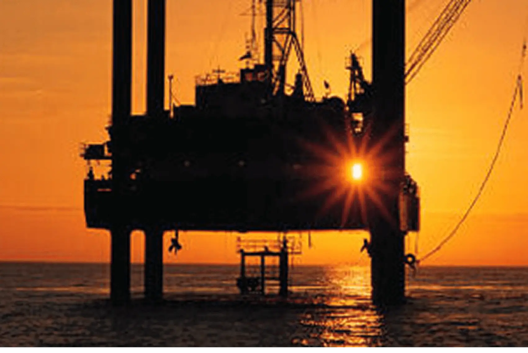Silhouette of oil rig at dusk.